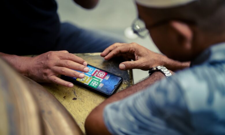 Two individuals play a mobile game on a smartphone outdoors in Jakarta, Indonesia.