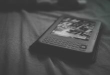 Black and white e-reader resting on patterned bedding, focusing on technology and reading.