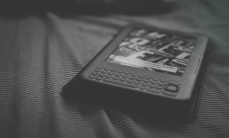 Black and white e-reader resting on patterned bedding, focusing on technology and reading.