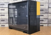 Modern computer case with glass panel, black and yellow design, on a wooden desk indoors.