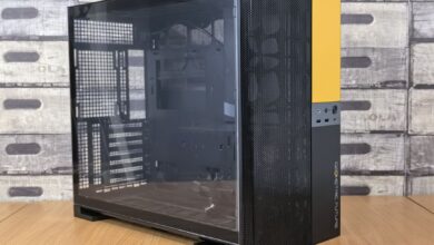 Modern computer case with glass panel, black and yellow design, on a wooden desk indoors.