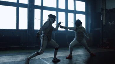 Two fencers engaged in a close indoor duel, showcasing dynamic action and skill.