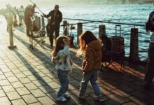 Two children play by the Bosphorus in Istanbul at sunset, with fishermen nearby.