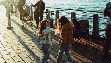 Two children play by the Bosphorus in Istanbul at sunset, with fishermen nearby.
