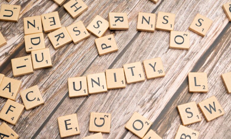 Scrabble tiles on a wooden surface spell 'Unity', highlighting teamwork and togetherness.