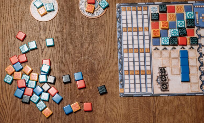 Top view of a strategy board game with colorful tiles and game board on a wooden table.