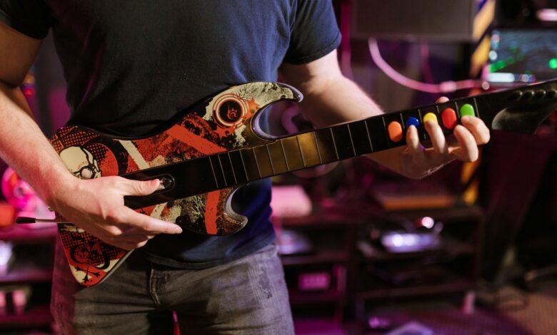 Close-up of a man playing a Guitar Hero controller indoors, featuring vibrant colors and technology.