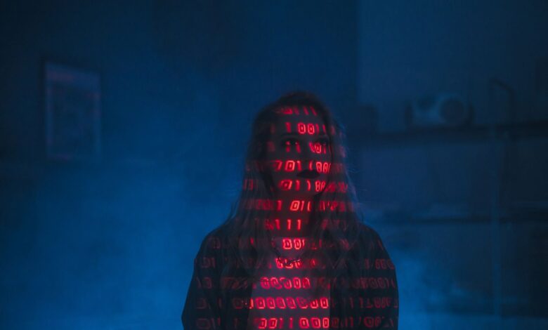 A mysterious silhouette with red binary code projected over the face, set against a dark, moody background.