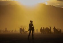 A dynamic silhouette of a person amidst a vibrant crowd against a dramatic sunset.
