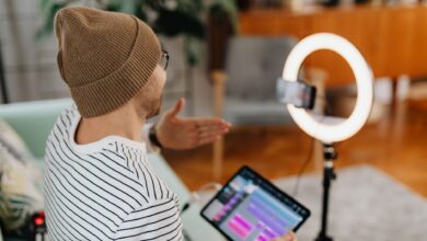 Adult male recording podcast using tablet and cellphone with ring light indoors
