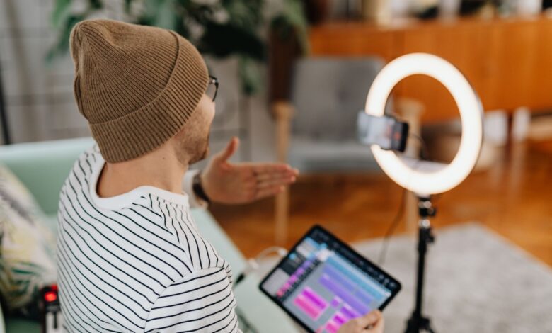 Adult male recording podcast using tablet and cellphone with ring light indoors