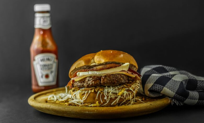 Mouth-watering gourmet burger with cheese and ketchup on wooden plate.