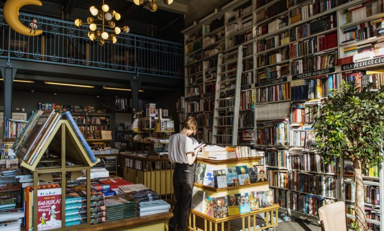A person enjoys a book in a sunlit, cozy bookstore filled with a variety of books.