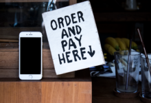 A phone next to an 'Order and Pay Here' sign in a cozy indoor setting, perfect for business use.