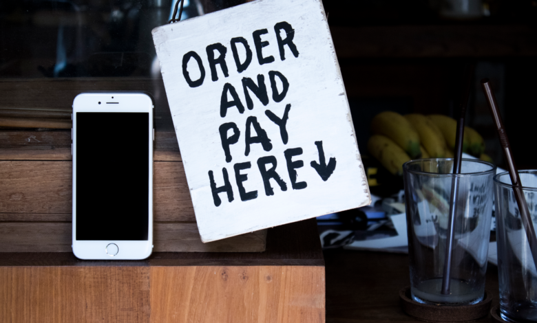 A phone next to an 'Order and Pay Here' sign in a cozy indoor setting, perfect for business use.