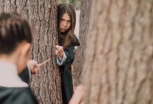 Children dressed as wizards play with magic wands in a forest setting, evoking fantasy and adventure.