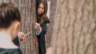 Children dressed as wizards play with magic wands in a forest setting, evoking fantasy and adventure.