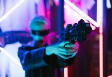 A woman in cyberpunk fashion holding a futuristic weapon against a neon backdrop.