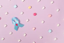 A blue diabetes awareness ribbon surrounded by candies on a pink pastel background promoting health awareness.