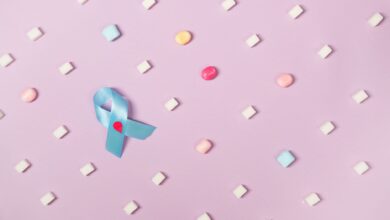 A blue diabetes awareness ribbon surrounded by candies on a pink pastel background promoting health awareness.
