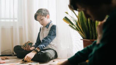 Kids enjoying an indoor tabletop card game in natural light, fostering leisure and strategy skills.