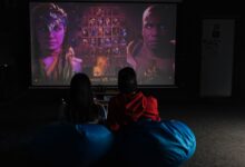 Two friends enjoying a video game session on a projector screen, immersed in gameplay.