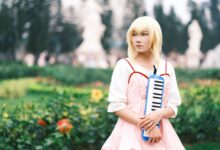 Captivating anime cosplay portrait featuring a person playing a melodica outdoors in Vietnam.