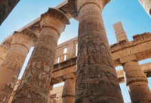 Impressive ancient Egyptian temple columns with hieroglyphics under a clear blue sky.