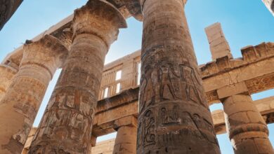 Impressive ancient Egyptian temple columns with hieroglyphics under a clear blue sky.