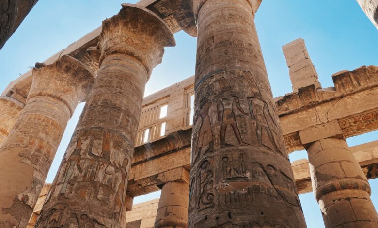 Impressive ancient Egyptian temple columns with hieroglyphics under a clear blue sky.