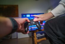 Close-up of hands using a game controller in a cozy living room setting.