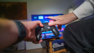 Close-up of hands using a game controller in a cozy living room setting.