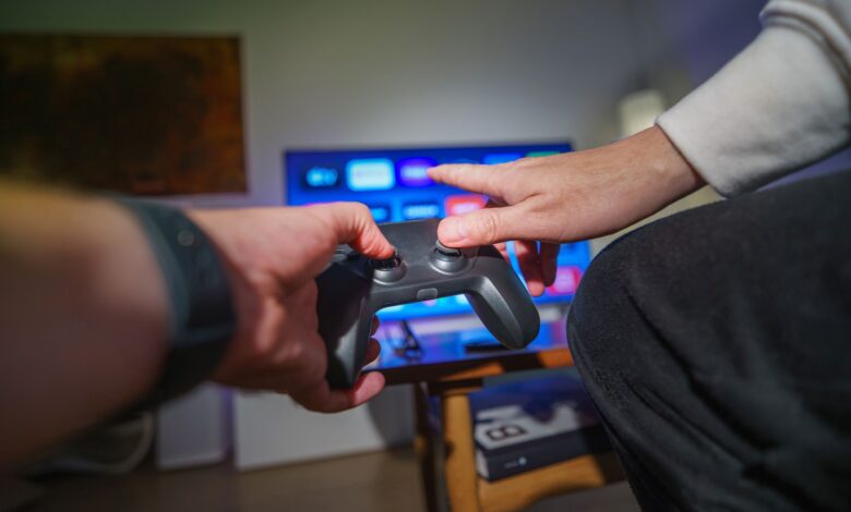 Close-up of hands using a game controller in a cozy living room setting.