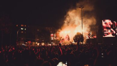 A dynamic live music concert with a large crowd, stage lights, and performer spotlight.