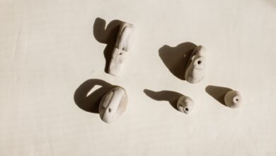 Artistic shot of handmade clay ocarinas on light background, highlighting shadows.