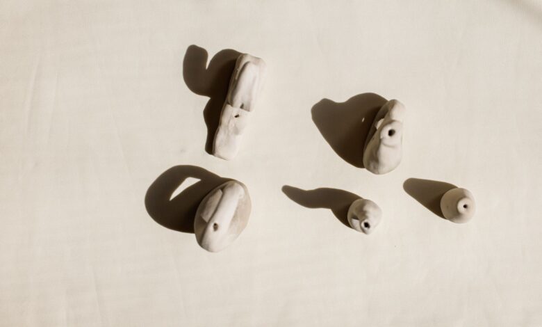 Artistic shot of handmade clay ocarinas on light background, highlighting shadows.