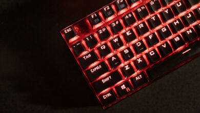 Close-up view of a red illuminated mechanical gaming keyboard in a dark room.