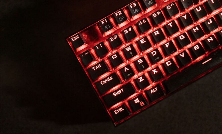 Close-up view of a red illuminated mechanical gaming keyboard in a dark room.