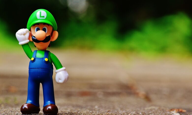 Close-up of a Luigi figurine from a videogame standing on outdoor pavement, showcasing fun and play.
