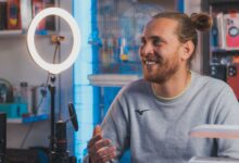 Smiling man with long hair recording content in a studio setting.