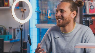 Smiling man with long hair recording content in a studio setting.