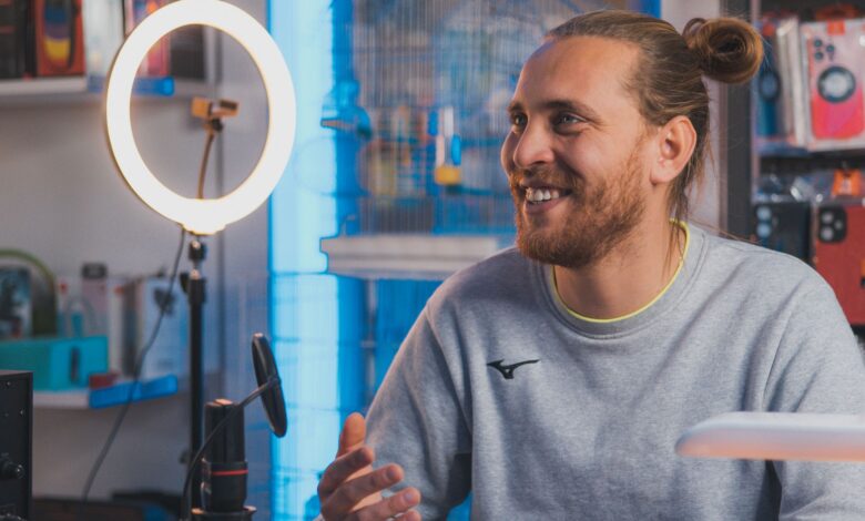 Smiling man with long hair recording content in a studio setting.