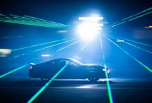 A car speeds through bright laser lights at night, creating dynamic light streaks.