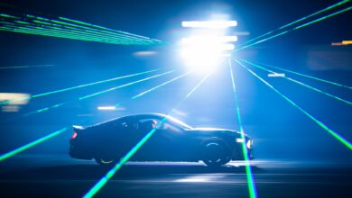 A car speeds through bright laser lights at night, creating dynamic light streaks.