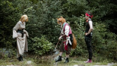 Fantasy characters engage in cosplay in a lush forest environment.