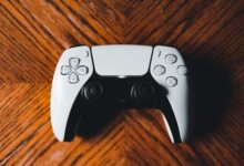 A detailed shot of a modern game controller on a richly textured wooden surface.