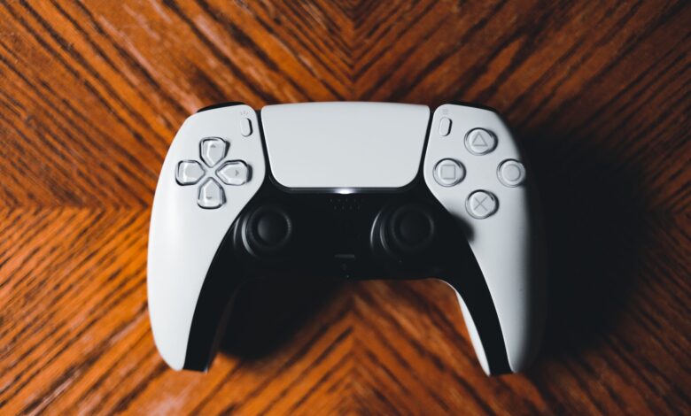 A detailed shot of a modern game controller on a richly textured wooden surface.