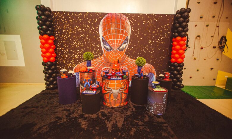 A colorful Spiderman themed birthday party decoration with balloons and figurines.