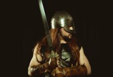 A medieval warrior wearing a helmet and leather armor, holding a sword, embodying the Viking spirit.