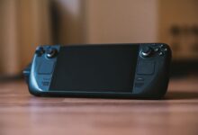 Modern handheld gaming console with buttons and joystick on a wooden surface, ideal for portable gaming enthusiasts.